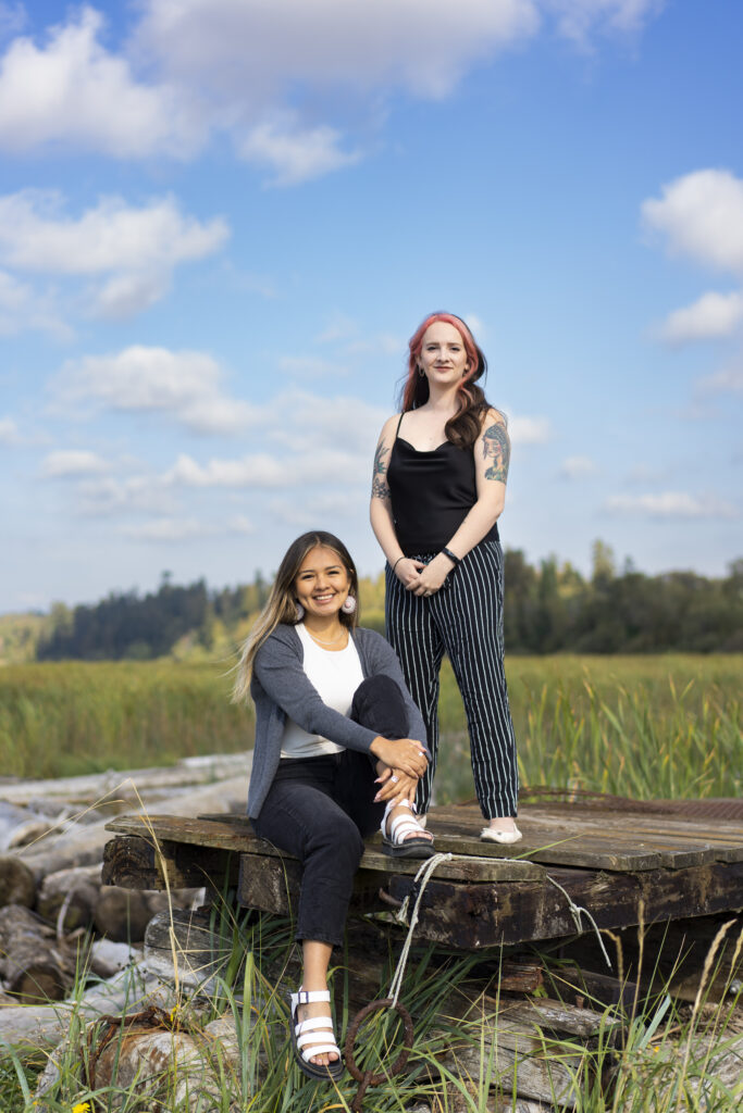 Two YPP participants face the camera proudly against a backdrop of an open field and clear skies.